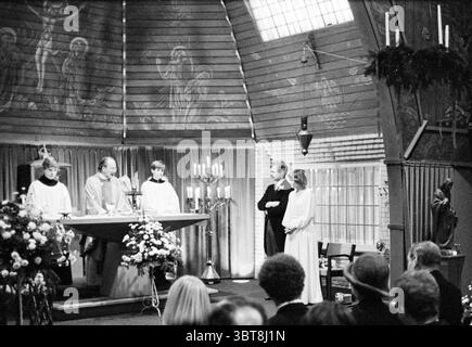 Mariage Ruigrok mariage, Whizgle News, Dutch Desk, pays-Bas, 1950 - 2000 le 16-12-1978. L'image montre ces rubriques. La scène se déroule dans un espace rustique et chaleureusement éclairé qui semble être une église ou une chapelle, caractérisée par ses murs et son plafond en bois. L'architecture a une sensation intime et chaleureuse, avec des éléments de vitraux qui diffusent une lumière douce dans toute la région. Au premier plan, un groupe d'individus se tient autour d'un autel. Deux hommes, probablement des officiants, portent des robes traditionnelles, dont un peut-être orné d'une étole. Ils s'engagent dans un rituel solennel, leurs expressions sérieuses Banque D'Images