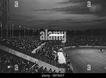 Sullivans - All Stars Baseball, Whizgle News, Dutch Desk, pays-Bas, 1950 - 2000 le 07-07-1963. L'image inclut ces rubriques. La scène présente un grand stade extérieur, rempli d'une foule dense de spectateurs. Les stands sont superposés, chaque niveau animant avec des gens, certains assis et d'autres debout, tous absorbés par anticipation. Les tenues des participants sont variées, avec de nombreux vêtements de sport décontractés, faisant allusion à une soirée chaude. Le ciel au-dessus de la tête est un gradient de bleu qui s'approfondit à l'approche de la nuit, dispersé avec des brins de nuages, ajoutant de la profondeur à l'atmosphère. L'ambiance est charge Banque D'Images