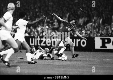 Football Haarlem - Ajax, Whizgle News, Dutch Desk, pays-Bas, 1950 - 2000 sur 09-1983. Ces rubriques sont illustrées dans l'image. La scène capture un moment d'action intense sur un terrain de football. Deux joueurs sont engagés dans une lutte acharnée, tous deux concentrés sur la balle qui se trouve entre eux. Un joueur, portant un maillot italien aux couleurs éclatantes, semble être à la mi-automne, suggérant qu'il a été frappé de déséquilibre. Son expression est une expression de détermination, mêlée à un soupçon de surprise ou de frustration. Le joueur adverse, vêtu d'un uniforme blanc contrasté, est à genoux, ayant juste fait Banque D'Images
