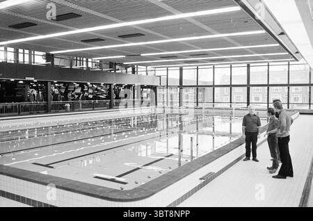 Piscine intérieure 'de Planet' Haarlem Planetenlaan pays-Bas, Whizgle News, Dutch Desk, pays-Bas, 1950 - 2000 on 12-1971. Ces rubriques apparaissent dans l'image. La scène se déroule dans une installation de baignade intérieure, caractérisée par une atmosphère spacieuse et aérée. Le centre d'attention est une grande piscine, sa surface d'eau calme reflétant les plafonniers et créant un effet chatoyant. Autour de la piscine, le sol est carrelé dans une couleur propre et discrète, ajoutant au sentiment général de l'ordre. La lumière naturelle inonde l'espace à travers de vastes panneaux de verre qui bordent un s. Banque D'Images