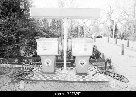 Pompe à essence IJweg contaminée IJweg, Whizgle News, Dutch Desk, pays-Bas, 1950 - 2000 le 30-03-1994. Ce sont les éléments de l'image. La scène présente une station-service vintage, caractérisée par deux pompes à carburant situées côte à côte. Chaque pompe est ornée de marques distinctes indiquant « Super plus » et « Diesel », bien que les couleurs soient atténuées, penchant vers une esthétique noir et blanc. La zone environnante dispose de carrelage sous les pompes, conçu dans un motif en damier qui ajoute un charme rétro subtil. Derrière les pompes, une végétation dense offre une toile de fond contrastée, avec lus Banque D'Images