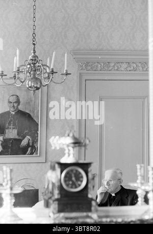 Mgr. Lescrauwaet, Whizgle News, Dutch Desk, pays-Bas, 1950 - 2000 on 16-10-1991. Ces rubriques apparaissent dans l'image. La scène représente un cadre intérieur serein, caractérisé par des tons doux et discrets qui créent un air de réflexion tranquille. Les murs sont ornés de motifs complexes, donnant un sentiment d'élégance à la pièce. Un grand lustre est suspendu au plafond, son design orné mis en valeur par la lueur chaude des chandelles, qui projette de douces ombres dans l'espace. Au premier plan, une horloge antique avec une finition en bois poli sert de point focal, sa présence mettant en valeur le R. Banque D'Images