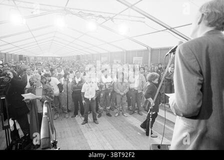 Manifestation de grève Hoogovens, Whizgle News, Dutch Desk, pays-Bas, 1950 - 2000 le 22-04-1991. Voici les rubriques de l'image. Un grand espace bondé est rempli d'un groupe diversifié de personnes, toutes rassemblées sous une structure ressemblant à une tente. Le cadre se caractérise par un sentiment d’anticipation et d’engagement. Des rangées d'individus sont vues, face à un haut-parleur positionné à l'avant ; l'atmosphère est à la fois sérieuse et concentrée. Les gens sont habillés dans une tenue de travail décontractée, avec beaucoup de vestes, jeans, et un mélange de couleurs claires et sombres. Certaines personnes semblent prendre des notes ou des holdin Banque D'Images