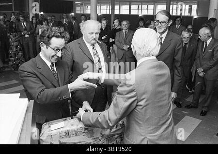 Adieu échevins de Beverwijk Conseil municipal de Beverwijk, Whizgle News, Dutch Desk, pays-Bas, 1950 - 2000 le 06-09-1974. Ces rubriques apparaissent dans l'image. Dans un cadre intérieur animé, un groupe d'hommes se tient à proximité, formant un demi-cercle autour d'une interaction centrale. L'atmosphère est formelle et quelque peu tendue, avec l'accent mis sur deux individus à l'avant-garde. Un homme, portant des lunettes avec des montures distinctes et un costume, sourit largement, étendant sa main vers l'avant à une autre figure qui est vêtue d'un costume plus léger. Ce deuxième individu semble plus stoïque et sérieux, eng Banque D'Images