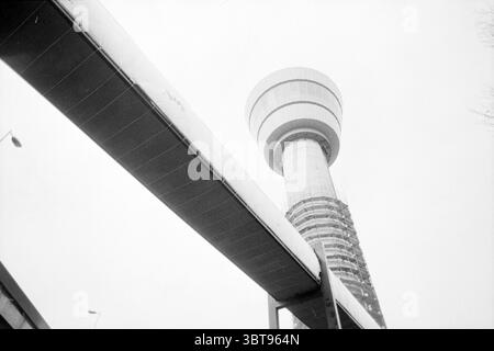 Tour de contrôle de Schiphol Schiphol Schiphol, Whizgle News, Dutch Desk, pays-Bas, 1950 - 2000 le 05-03-1990. Ces rubriques sont illustrées dans l'image. La scène capture un paysage urbain saisissant dominé par une structure imposante qui ressemble à une tour d'observation futuriste. La tour est cylindrique et présente un design élégant et moderne, caractérisé par des surfaces lisses et une large plate-forme d'observation en forme de disque près du sommet. Son extérieur est marqué par une combinaison de nuances claires et sombres, contribuant à une palette monochromatique, qui renforce sa présence imposante sur fond de couvert Banque D'Images