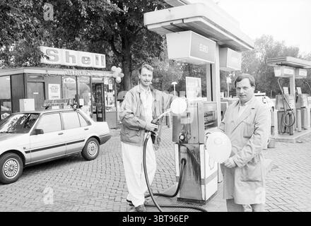Deux hommes à la station de pompage Shell Van Bugnum à Santpoort Santpoort, Whizgle News, Dutch Desk, pays-Bas, 1950 - 2000 le 02-10-1989. Voici les rubriques de l'image. La scène montre deux hommes debout à une station-service, tous deux tenant des ballons blancs. Ils sont positionnés à côté d'une pompe à carburant, qui a un grand affichage clair indiquant le prix en euros. Les hommes sont habillés de vêtements de couleur claire ; l'un porte un blazer et un pantalon de couleur claire, tandis que l'autre porte un trench-coat beige. Leurs expressions semblent joyeuses, suggérant une atmosphère festive. La station-service elle-même a un retrait Banque D'Images