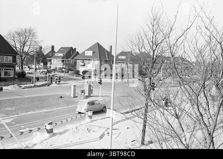 Aperçu du croisement Heemsteedse Dreef aperçus Heemstede Heemsteedse Dreef pays-Bas, Whizgle News, Dutch Desk, pays-Bas, 1950 - 2000 sur 26-02-1968. L'image contient ces rubriques. La scène capture une banlieue animée caractérisée par un mélange d'architecture résidentielle et commerciale. Les bâtiments, principalement de deux ou trois étages, présentent une variété de styles, avec des caractéristiques importantes telles que des toits à pente abrupte et de grandes fenêtres. Certaines structures possèdent des éléments décoratifs, renforçant leur charme et leur caractère. Au premier plan, une intersection circulaire est présente, Banque D'Images
