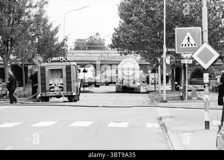 Pompiers sur camion-citerne coincé sous le viaduc de Julianalaan Overveen Julianalaan, Whizgle News, Dutch Desk, pays-Bas, 1950 - 2000 on 16-10-1978. Ces rubriques apparaissent dans l'image. La scène représente un environnement urbain animé capturé en monochrome, présentant un contraste saisissant entre la lumière et l'ombre. Au premier plan, un camion de pompiers, caractérisé par sa conception compacte et divers équipements de lutte contre l'incendie, est stationné avec un tuyau qui s'étend sur le trottoir, laissant entendre une intervention d'urgence continue. Ses surfaces métalliques brillent légèrement sous la lumière disponible. A gauche, un groupe Banque D'Images