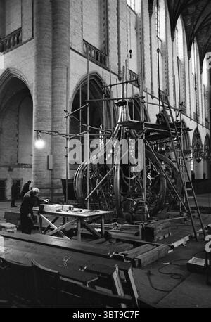 Travail sur l'oignon de la Grote ou Sint-Bavokerk tapant les spinnacles avec le plomb Grote Kerk Haarlem églises produit Bavokerk travail Haarlem Grote Markt pays-Bas, Whizgle News, Dutch Desk, pays-Bas, 1950 - 2000 on 02-02-1965. L'image montre ces rubriques. La scène capture l'intérieur d'un vaste espace ressemblant à une cathédrale caractérisé par de hautes arches en pierre et de grandes fenêtres éclairées qui laissent passer la lumière douce et diffuse. L'architecture transmet un sentiment de grandeur, avec les hauts plafonds accentuant la hauteur et l'espace de l'environnement. Au premier plan, une méta Banque D'Images
