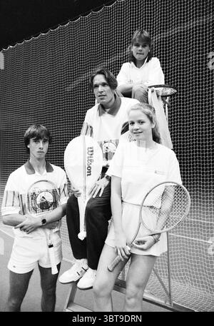 Joueurs de tennis, Whizgle News, Dutch Desk, pays-Bas, 1950 - 2000 le 09-04-1989. Ce sont les éléments de l'image. La scène présente une composition dynamique mettant en vedette quatre individus sur un court de tennis. L'arrière-plan est dominé par un grand filet en maille sombre qui s'étend à travers l'espace, mettant l'accent sur le thème sportif. Au premier plan, deux individus se tiennent côte à côte : un jeune homme aux cheveux courts et soignés portant une tenue de tennis blanche, avec une chemise et un short qui affichent des lignes subtiles et des motifs typiques des vêtements de sport. Il tient une raquette de tennis dans une main, la reposant Banque D'Images
