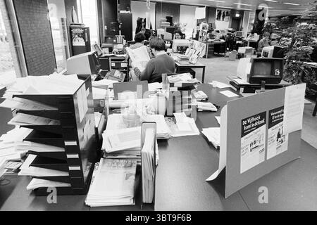 Rentokil - air Treatment HD, Whizgle News, Dutch Desk, pays-Bas, 1950 - 2000 le 23-03-1992. Ce sont les éléments de l'image. La scène se déroule dans un environnement de bureau animé, caractérisé par un mélange de chaos organisé et de divers postes de travail. Une grande table occupe le centre, encombrée de piles de papiers, de dossiers et de fichiers qui créent une tapisserie visuellement riche de tons blancs et beiges. Certains documents sont soigneusement disposés dans des supports, tandis que d'autres sont éparpillés à la surface dans le désordre, ce qui fait allusion à une culture de travail occupée. En arrière-plan, plusieurs postes de travail peuvent être vus, wit Banque D'Images