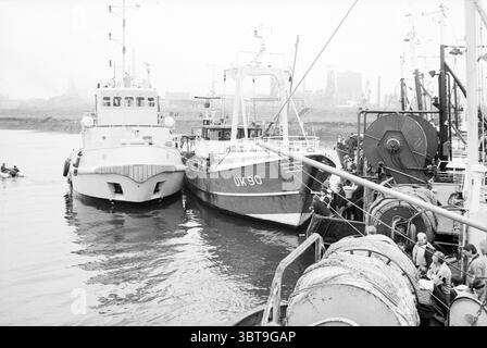 Briser le blocus des navires de pêche IJmuiden Fisheries et autres poissonniers pêchant IJmuiden pays-Bas, Whizgle News, Dutch Desk, pays-Bas, 1950 - 2000 on 28-10-1987. Ces rubriques apparaissent dans l'image. La scène représente un port animé, où plusieurs bateaux sont amarrés étroitement ensemble. Deux vaisseaux proéminents dominent le premier plan ; l'un est blanc et élégant, tandis que l'autre est bleu foncé avec un numéro d'enregistrement visible, suggérant une activité et un but. L'eau est légèrement ondulée, reflétant le ciel couvert, qui projette une lumière grise et silencieuse sur la zone. Ce Li atmosphérique Banque D'Images