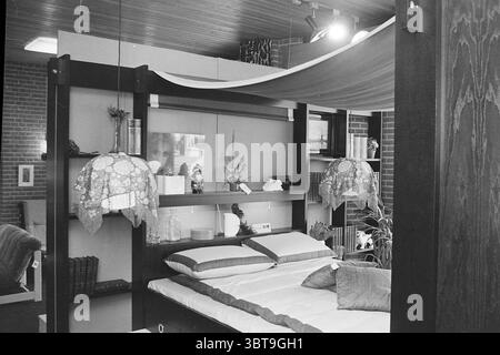 Intérieur de Van Duijvenboden intérieur Haarlem Gedempte Oude Gracht 90 pays-Bas, Whizgle News, Dutch Desk, pays-Bas, 1950 - 2000 on 28-03-1973. L'image inclut ces rubriques. La scène dispose d'une chambre confortable avec une esthétique de design moderne. Au centre de la composition se trouve un lit bas et minimaliste avec un matelas de couleur claire, surmonté d'oreillers élégants aux textures variées. Au-dessus du lit, un auvent en tissu doux est suspendu, créant un sentiment d'intimité et de chaleur. Les murs sont ornés d'un mélange de tons naturels et neutres, contrastant avec le bois sombre du cadre du lit. Un Ser Banque D'Images