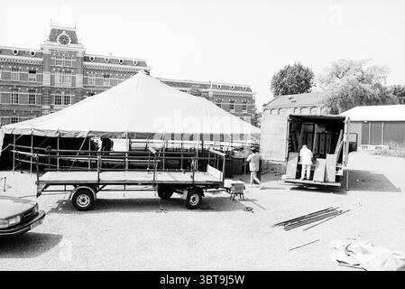 Construction d'une tente de cirque sur le site de l'ancienne caserne Ripperda Haarlem Schoterweg pays-Bas, Whizgle News, Dutch Desk, pays-Bas, 1950 - 2000 le 19-07-1995. Ces rubriques apparaissent dans l'image. La scène est un cadre extérieur caractérisé par une grande structure recouverte de tissu au centre, soutenue par un cadre métallique. La tente est dressée sur une surface de gravier, ce qui indique qu'elle sert un but, peut-être un rassemblement ou un événement. Autour de la tente, plusieurs individus sont présents, occupés par les préparatifs. Deux personnes sont engagées dans des activités liées au déchargement d'un camion stationné Banque D'Images