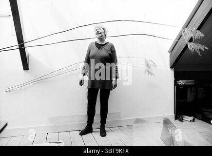 Marijke Don en studio, Whizgle News, Dutch Desk, pays-Bas, 1950 - 2000 le 18-04-1996. Voici les rubriques de l'image. Dans un espace intérieur minimaliste, une femme se tient en toute confiance contre un mur de couleur claire qui jette une atmosphère sereine. Les tons doux et neutres du mur complètent les tons de bois naturel du sol, qui a un charme rustique avec sa finition légère. La femme est habillée dans un pull confortable et surdimensionné qui drape confortablement sur sa silhouette, associé à des leggings noirs ajustés qui créent un look épuré et élégant. Ses cheveux sont coiffés de façon décontractée, ajoutant à la vib décontractée Banque D'Images