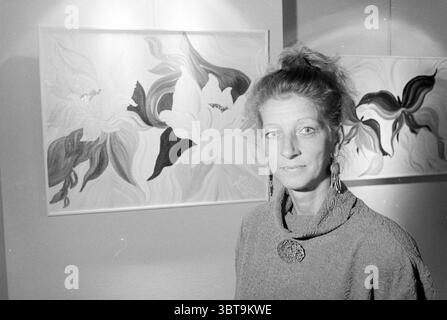 Laura dekker exposition IJmuiden Theater IJmuiden pays-Bas, Whizgle News, Dutch Desk, pays-Bas, 1950 - 2000 le 08-09-1992. L'image inclut ces rubriques. Dans la scène, une femme se tient bien en vue au premier plan, dégageant un comportement calme et confiant. Elle a des cheveux de couleur claire, coiffés lâchement, et porte un pull à manches longues à texture complexe qui semble doux et invitant. Une broche distinctive orne son pull, attirant l'attention avec son design unique. Derrière elle, deux grandes peintures accrochées au mur présentent des motifs floraux abstraits et vibrants. Les fleurs sont rendues Banque D'Images