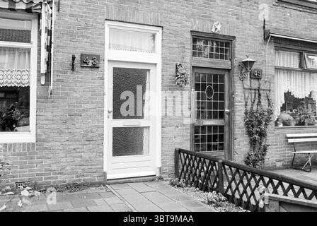 2 portes d'entrée Tuinderstraat IJmuiden maisons et construction de logements IJmuiden Velsen IJmuiden Tuindersstraat pays-Bas, Whizgle News, Dutch Desk, pays-Bas, 1950 - 2000 on 24-09-1981. L'image montre ces rubriques. La scène met en valeur un charmant cadre résidentiel en briques, caractérisé par deux portes adjacentes, numérotées 43 et 45. La texture des briques rouges est proéminente, créant une toile de fond chaleureuse et accueillante. La porte de gauche est peinte en blanc, avec un panneau de verre dépoli qui laisse passer la lumière douce, ajoutant une touche d'élégance. A sa droite, le bois sombre Banque D'Images