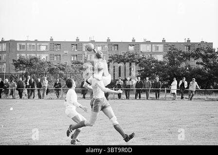 VVB - Zandvoortmeeuwen Football VVB, Whizgle News, Dutch Desk, pays-Bas, 1950 - 2000 le 10-09-1967. Ces rubriques apparaissent dans l'image. Dans une scène sportive dynamique, deux joueurs sont engagés dans un moment tendu d'un match de football. Un athlète, portant un maillot blanc, saute dans les airs, les bras tendus, tentant d'attraper le ballon. Son expression focalisée souligne l'intensité du jeu. Le deuxième joueur, vêtu d'un kit bleu clair, lève les yeux par anticipation et se positionne défensivement. Autour d'eux, l'herbe verte luxuriante du champ contraste avec les tons sourds du pla Banque D'Images