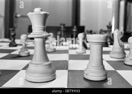 Joueur d'échecs Alexandra (Käty) van der Mije - Nicolau Grandmaster Chess, Whizgle News, Dutch Desk, The Netherlands, 1950 - 2000 le 05-11-1975. Ces rubriques apparaissent dans l'image. La scène présente une vue rapprochée d'un échiquier, caractérisé par une palette de couleurs noire et blanche. La planche elle-même est disposée dans un motif classique alternant de carrés sombres et clairs, créant une grille qui attire le regard sur la surface de jeu. Au premier plan, des pièces proéminentes se distinguent, notamment une grande pièce royale élégamment conçue, son sommet lisse et arrondi et sa stature imposante lui donnant une impression de A. Banque D'Images