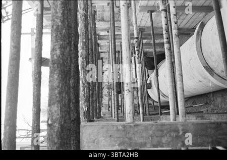 Ouvrages d'assainissement Parklaan Works Haarlem Parklaan pays-Bas, Whizgle News, Dutch Desk, pays-Bas, 1950 - 2000 on 15-12-1965. Ce sont les éléments de l'image. La scène capture un chantier de construction caractérisé par une esthétique brutale et utilitaire. Les poutres en bois verticales sont hautes, formant un cadre squelettique qui fait allusion à la structure émergente. Ces poutres sont entrecoupées d'échafaudages métalliques, créant un motif en forme de grille qui attire l'œil vers le haut. Au premier plan, un grand objet cylindrique, éventuellement une bétonnière ou un conteneur de stockage, occupe une position proéminente. Banque D'Images