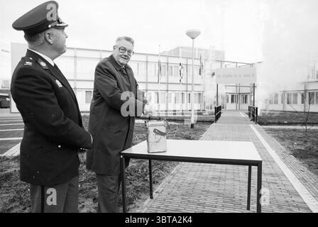 Ouverture du poste de police de Bloemendaal par le Commissaire de la Reine en Hollande du Nord Roel de Wit Bloemendaal, Whizgle News, Dutch Desk, pays-Bas, 1950 - 2000 le 07-12-1989. L'image montre ces rubriques. Dans un cadre monochrome, deux hommes se tiennent à l'extérieur d'un bâtiment institutionnel moderne caractérisé par des lignes épurées et un design fonctionnel. La façade du bâtiment présente de grandes fenêtres qui reflètent l’environnement environnant, tandis que son entrée est encadrée par un simple auvent sans ornement. L'homme à gauche, vêtu d'un uniforme de police sombre orné d'insignes, se tient debout avec une expression composée, Banque D'Images