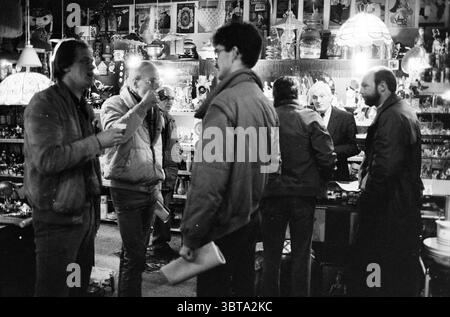 Promotion ecd au marché noir B'wijk Markt Beverwijk pays-Bas, Whizgle News, Dutch Desk, pays-Bas, 1950 - 2000 le 03-02-1985. Voici les rubriques de l'image. La scène représente une boutique d'antiquités animée remplie d'un éventail d'objets de collection et d'objets vintage. Divers objets, tels que des lampes ornées, des figurines et des images encadrées, créent une riche tapisserie de textures et de formes qui attirent le regard. La douce lueur de l'éclairage chaud des lampes projette des ombres douces, améliorant l'atmosphère chaleureuse et dynamique. Au premier plan, trois individus sont engagés dans une conversation animée. Un p Banque D'Images