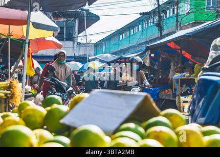 Balikpapan, Indonésie – 19 avril 2025. Scène de marché de rue bondée avec des motos, des étals de fruits et des acheteurs locaux. Banque D'Images