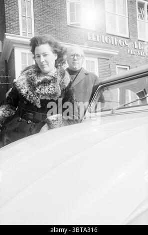 Homme et femme à l'échelle et au bâtiment de l'association de la NED. Église réformée.., Whizgle News, Dutch Desk, pays-Bas, 1950 - 2000. Ce sont les éléments de l'image. La scène présente deux figures au premier plan, créant une composition dynamique et engageante. Au centre, une femme se tient confiante, sa posture détendue mais affirmée. Elle est habillée d'un manteau élégant orné d'accents de fourrure, ce qui ajoute texture et sophistication. Le pelage est sombre, contrastant avec son teint plus clair et ses cheveux, qui apparaissent ondulés et sont élégamment stylisés. Derrière elle, un homme est positionné, glissant Banque D'Images