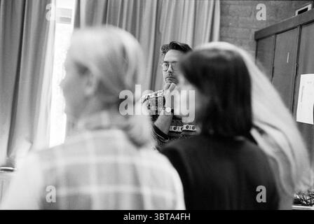 Répétition Cendrillon, Whizgle News, Dutch Desk, pays-Bas, 1950 - 2000 on 02-06-1995. Ces rubriques apparaissent dans l'image. La scène met en scène un petit groupe de personnes engagées dans une conversation, probablement dans un cadre intérieur. Au premier plan, deux femmes peuvent être vues de derrière. On a des cheveux légers et fluides et porte un vêtement à carreaux aux tons clairs, qui ajoute une sensation de douceur à la scène. L'autre femme, visible avec des cheveux plus foncés, porte une tenue élégante et sombre qui contraste avec la tenue plus claire de son compagnon. En arrière-plan, un homme avec des lunettes, habillé d'un haut à motifs, Banque D'Images