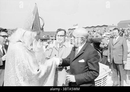 Ouverture du parking Raaks à Haarlem, Whizgle News, Dutch Desk, pays-Bas, 1950 - 2000 le 21-04-1971. Ces rubriques sont illustrées dans l'image. Dans un cadre extérieur animé, un rassemblement de personnes est visible, indiquant une ambiance festive. Au centre de la scène se trouve un homme âgé vêtu d'une tenue traditionnelle élaborée ressemblant à celle d'un saint, avec une longue barbe blanche et un chapeau pointu orné de motifs complexes. Ses robes richement colorées ont une qualité chatoyante, suggérant une présence royale. Autour de lui se trouvent plusieurs individus, certains habillés de costumes et de cravates, hig Banque D'Images