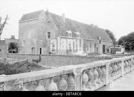 Old Heemstede Castle Ruin, Whizgle News, Dutch Desk, pays-Bas, 1950 - 2000 on 07-06-1968. L'image montre ces rubriques. La scène représente un grand bâtiment traditionnel en briques caractérisé par sa forme rectangulaire robuste et ses caractéristiques architecturales distinctes. La structure est principalement construite en briques rouges et grises, affichant un style hollandais classique, avec un toit fortement incliné couvert de tuiles d'ardoise. De hautes fenêtres étroites ponctuent la façade, offrant un aperçu de la lumière de l'intérieur, tandis qu'une grande arche centrale invite l'entrée. Au premier plan, une pierre ornementale robuste b Banque D'Images