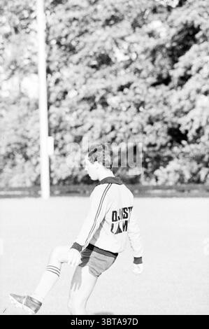 Portrait M. Schutter joueur de football HBC Football People and entraîneurs, Whizgle News, Dutch Desk, pays-Bas, 1950 - 2000 le 16-08-1978. L'image montre ces rubriques. Dans un champ herbeux, un jeune homme est capturé à mi-mouvement alors qu'il se prépare à frapper un ballon de football. Il est habillé d'une veste légère avec des rayures audacieuses et contrastées et un short de sport court, incarnant une énergie vigoureuse et jeune. Le cadre présente de l'herbe verte luxuriante, légèrement floue en arrière-plan, sur un doux fond d'arbres, évoquant un environnement serein et naturel. L'éclairage est lumineux mais doux, suggérant e Banque D'Images