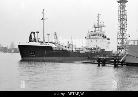 Neptune : drague à trémie fendue à Scheepswerf Stapel Spaarndam Schepen Spaarndam, Whizgle News, Dutch Desk, pays-Bas, 1950 - 2000 on 07-04-1983. Ce sont les éléments de l'image. La scène présente un grand cargo, bien visible comme sujet central. Sa coque est peinte d'un noir dur, contrastant avec le gris discret d'une atmosphère brumeuse. Le pont supérieur comporte une superstructure blanche ornée d'une série d'antennes et d'équipements, indiquant sa fonctionnalité pour les opérations maritimes. Autour du navire se trouve une étendue d'eau calme, reflétant la lumière douce et diffuse Banque D'Images
