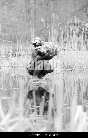 Sculpture 'Leda et le cygne' par Nic. Jonque dans Velserbeek Park Velsen, Whizgle News, Dutch Desk, The Netherlands, 1950 - 2000 sur 21-04-1994. Ces rubriques sont illustrées dans l'image. Dans un cadre serein, une statue en pierre altérée occupe le devant de la scène, représentant un personnage pendu tout en agrippant un grand animal. La statue, finement sculptée, affiche un mélange de force et de délicatesse dans ses caractéristiques, soulignant le lien étroit entre la figure et son compagnon. La surface de la statue montre des signes d'âge, avec des textures qui ajoutent un sens de l'histoire et de la permanence. Entourant la statue, un bod encore Banque D'Images