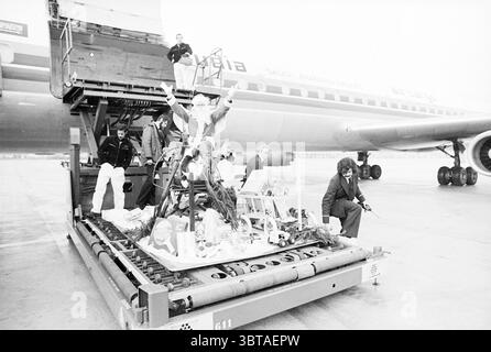 Mise en service de la plate-forme de fret de Schiphol mise en service mise en service de Schiphol, Whizgle News, Dutch Desk, pays-Bas, 1950 - 2000 le 14-12-1977. Ces rubriques sont illustrées dans l'image. La scène capture un environnement aéroportuaire animé, mis en évidence par plusieurs personnes engagées dans diverses activités autour d'un grand dispositif de chargement de fret. Au premier plan, un groupe d'individus est rassemblé, certains avec des expressions exubérantes, suggérant une atmosphère joyeuse. Une personne se tient debout avec les bras levés triomphalement, tandis que d'autres sont occupés à organiser des objets. Habillé dans un mélange de tenues décontractées et semi-formelles Banque D'Images