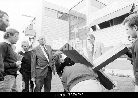 Ouverture du nouveau complexe NS Oudeweg ouverture ouverture commissionnement chemins de fer Haarlem Voormalige Oudeweg pays-Bas, Whizgle News, Dutch Desk, pays-Bas, 1950 - 2000 on 10-10-1986. Ces rubriques apparaissent dans l'image. Un groupe d'individus se réunit à l'extérieur d'un bâtiment moderne caractérisé par un design élégant et angulaire, avec de grandes fenêtres en verre et un extérieur propre dans des tons de gris. La scène se déroule sur une journée nuageuse, avec un éclairage doux et diffus qui crée une atmosphère sereine. Au premier plan, quelques hommes sont engagés dans une activité impliquant une grande croix de bois, qui est tenue vers le haut b Banque D'Images