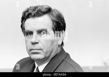 Portraits de Mr. menting, Whizgle News, Dutch Desk, pays-Bas, 1950 - 2000 le 14-11-1991. Ce sont les éléments de l'image. La scène montre un homme avec des cheveux distincts et soigneusement soignés qui encadrent son visage, lui donnant une apparence digne. Il a une expression sérieuse, caractérisée par des yeux profonds et un front légèrement sillonné, véhiculant un sentiment de contemplation ou de détermination. Sa tenue est formelle, avec une veste sombre sur une chemise de couleur claire, ce qui suggère qu'il peut être dans un cadre professionnel ou formel. L'arrière-plan est légèrement flou, indiquant un environnement minimaliste et discret Banque D'Images