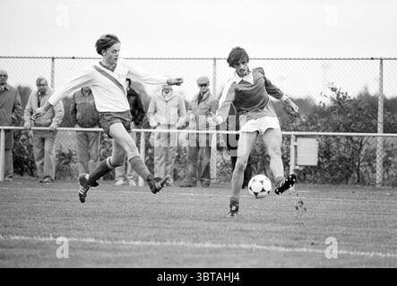 Terrasvogels - DSOV Football, Whizgle News, Dutch Desk, pays-Bas, 1950 - 2000 on 05-10-1980. Voici les rubriques de l'image. Dans une scène sportive animée, deux athlètes sont capturés au milieu d'un match de football dynamique sur un terrain herbeux. Les joueurs portent des uniformes distincts : l'un dans une chemise blanche à manches longues avec un short rouge et l'autre dans une chemise rouge à manches courtes jumelée à un short blanc. Leurs expressions sont intenses, témoignant de leur détermination et de leur concentration lorsqu'ils s'affrontent pour le ballon, qui est positionné au centre du cadre. L'arrière-plan comporte un groupe de spectateurs, habillé i. Banque D'Images