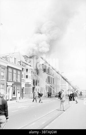 Incendie Haymarket Fire brigade Haarlem Hooimarkt pays-Bas, Whizgle News, Dutch Desk, pays-Bas, 1950 - 2000 on 26-06-1980. Voici les rubriques de l'image. Dans un cadre urbain animé, une scène dramatique se déroule sous forme d'épais panaches de fumée sombre provenant des étages supérieurs d'une rangée de bâtiments. La structure semble être une maison traditionnelle de deux ou trois étages, caractérisée par des briques et une architecture détaillée. Les flammes sont partiellement visibles à travers les fenêtres, ce qui laisse entendre l'intensité du feu. Les pompiers, vêtus d'un équipement de protection, sont engagés dans l'intervention d'urgence, en utilisant Banque D'Images