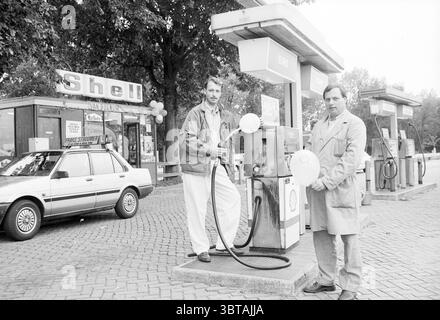 Deux hommes à la station de pompage Shell Van Bugnum à Santpoort Santpoort, Whizgle News, Dutch Desk, pays-Bas, 1950 - 2000 le 02-10-1989. Voici les rubriques de l'image. Dans une station-service animée, deux hommes se tiennent bien en vue à côté d'une pompe à carburant à l'ancienne. Ils portent tous les deux des tenues de couleur claire, l'une dans une veste ample et l'autre dans un manteau long. Leurs expressions semblent détendues mais engagées, créant un sentiment de camaraderie car ils tiennent des buses de pompe à essence blanches, se préparant probablement à faire le plein d'un véhicule. L'arrière-plan présente une structure de station-service avec un style distinct, en partie obscur Banque D'Images
