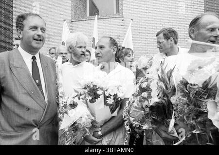 Croix-Rouge Walking Tour arrivée Marche, Whizgle News, Dutch Desk, pays-Bas, 1950 - 2000 on 10-09-1988. Voici les rubriques de l'image. La scène capture un groupe d'individus rassemblés à l'extérieur, dégageant un sentiment de célébration ou de réussite. L'atmosphère est remplie d'une ambiance animée, tandis que les participants arborent des sourires lumineux et affichent un air de camaraderie. Au premier plan, plusieurs hommes se tiennent étroitement ensemble, chacun berçant un assortiment de fleurs, principalement dans des couleurs pastel comme le blanc et le rose doux, qui ajoute une touche de chaleur à la scène. Les fleurs sont luxuriantes, ce qui fait allusion Banque D'Images