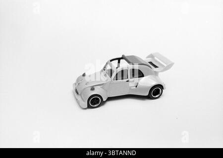 Ugly Duck Models Automobilia, Whizgle News, Dutch Desk, pays-Bas, 1950 - 2000 sur 13-08-1990. Ces rubriques apparaissent dans l'image. La scène présente une petite voiture jouet élégante, présentant une surface lisse et brillante avec une finition métallique légère. Son corps est principalement argenté, scintillant subtilement sous un éclairage doux et diffus. La voiture jouet est conçue avec une forme compacte, avec des bords arrondis et une forme ludique et aérodynamique, soulignée par une aile arrière qui ajoute une touche de sportivité. Les roues sont détaillées, affichant de petits pneus noirs avec des accents blancs, lui donnant une ambiance vive et énergique. Banque D'Images