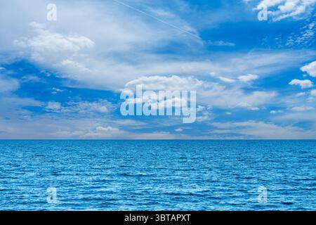 Vaste vue sur l'océan sous un ciel bleu lumineux avec des nuages blancs moelleux, paysage marin serein Banque D'Images
