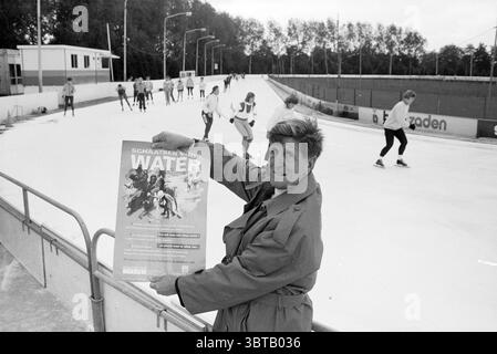 M. van de Reyden à la patinoire en raison de la campagne Skating for Water pour le Foster parents Plan Haarlem pays-Bas, Whizgle News, Dutch Desk, pays-Bas, 1950 - 2000 le 08-10-1990. L'image contient ces rubriques. Dans un cadre de patin à glace récréatif, la scène est animée d'activités. Une figure éminente se tient à l'avant-garde, tenant une grande affiche, qui semble attirer l'attention. La personne semble habillée d'un manteau de couleur claire, suggérant un froid dans l'air typique d'un environnement de patinoire. Leur expression exprime de l'enthousiasme, peut-être en promouvant l'événement ou la cause du représentant Banque D'Images
