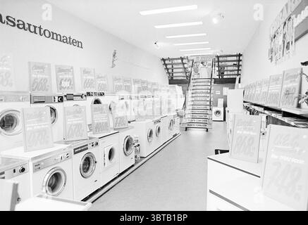 Salle de lave-linge Grote Houtstraat intérieur Haarlem Grote Houtstraat pays-Bas, Whizgle News, Dutch Desk, pays-Bas, 1950 - 2000 on 29-09-1972. L'image contient ces rubriques. La scène capture un cadre intérieur spacieux, mettant en vedette une rangée de machines à laver alignées sur un fond épuré et minimaliste. Les couleurs dominantes sont atténuées, avec des nuances de blanc et de gris créant une esthétique épurée et moderne. Les machines sont principalement blanches, avec quelques notes argentées, contribuant à une atmosphère stérile mais invitante. En arrière-plan, un escalier monte, menant à un niveau supérieur, hi Banque D'Images