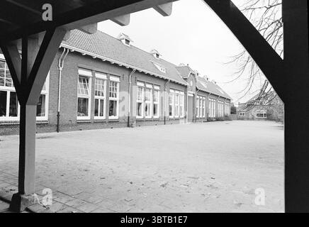School de Akker Schoolstraat 11a lisse Schoolstraat, Whizgle News, Dutch Desk, pays-Bas, 1950 - 2000 on 13-11-1980. L'image contient ces rubriques. La scène présente une ambiance sombre et solennelle, avec une cour devant un long bâtiment en briques. L'architecture est caractérisée par une série de grandes fenêtres qui sont alignées symétriquement le long de l'extérieur. Le bâtiment a un charme classique et utilitaire, avec ses briques rouge foncé contrastant avec le ciel gris et couvert. La cour est principalement vide, avec une surface lisse et pavée qui s'étend vers le bâtiment, showcas Banque D'Images