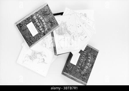 Star Box, Whizgle News, Dutch Desk, pays-Bas, 1950 - 2000 le 21-08-1994. Voici les rubriques de l'image. La scène présente une collection de cartes au design complexe dispersées sur une surface. Ces cartes présentent des illustrations éclatantes, principalement dans des tons de bleu, d'or et de pastel doux, qui créent un contraste visuel attrayant. L'imagerie capture des thèmes célestes, représentant peut-être des signes ou des constellations du zodiaque, avec des figures élégamment illustrées dans des poses dynamiques. Entourant les cartes est une boîte rectangulaire, partiellement visible, suggérant qu'une fois les cartes tenues ensemble Banque D'Images