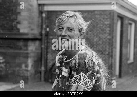Monique Diederichs Mephisto, Whizgle News, Dutch Desk, pays-Bas, 1950 - 2000 le 29-08-1995. Ce sont les éléments de l'image. La scène capture une femme avec un sourire radieux, mettant en valeur un sentiment de chaleur et d'accessibilité. Ses longs cheveux de couleur claire sont légèrement émoussés, attrapant la brise et ajoutant un élément dynamique à sa présence. Elle porte un pull confortable à motifs avec des motifs complexes dans des couleurs douces et discrètes qui évoquent un sentiment de confort et un style décontracté. En arrière-plan, un mur de briques texturé suggère un cadre urbain, avec des tons de terre sourds et des variations subtiles Banque D'Images