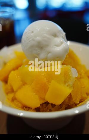 Crème glacée à la mangue avec garniture de mangue fraîche dans un bol blanc Banque D'Images