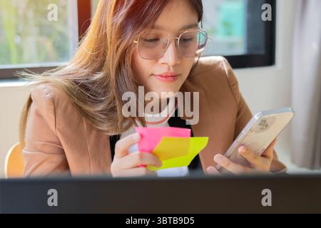 Femme d'affaires professionnelle réussie asiatique employée en costume formel assis souriant au bureau du poste de travail avec ordinateur Banque D'Images